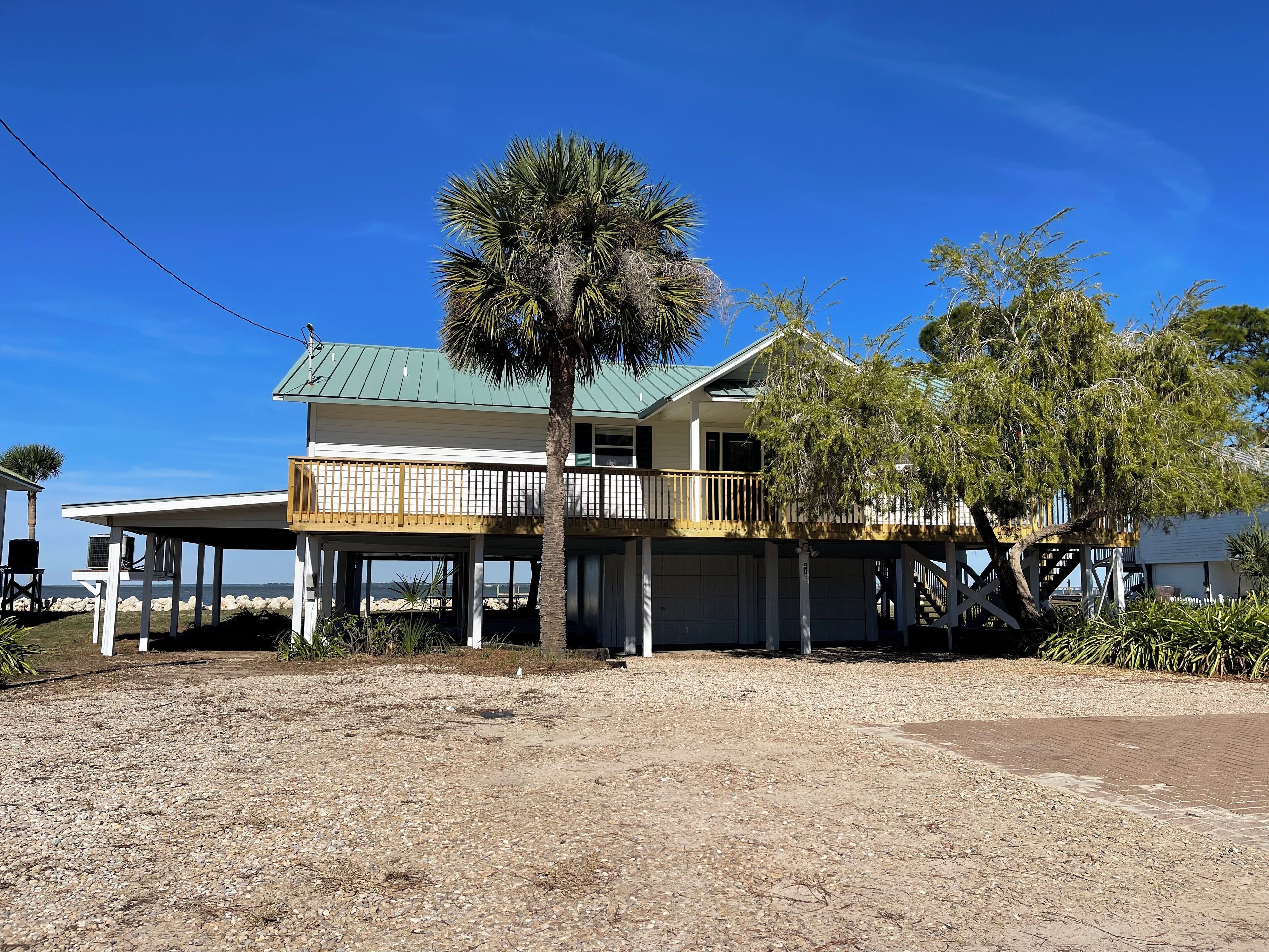 A two-story house with a green roof, a balcony, and a covered porch area.