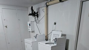 Une buanderie équipée de deux machines à laver et d’un panneau électrique fixé au mur.