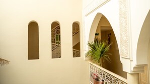 A courtyard with white walls, arched windows, and a palm tree. - Riad Jaia (Marrakech)