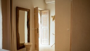 A hotel hallway with a large mirror, a toilet, and a door leading to another room. - Riad Jaia (Marrakech)