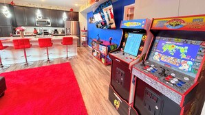 Une cuisine moderne avec des meubles de couleur sombre, un réfrigérateur en acier inoxydable et un coin bar rouge agrémenté de tabourets.