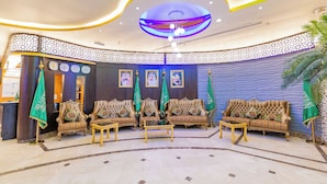 A lobby with a reception desk, sofas, and a patterned wall. - Sama Almisk Hotel (Makkah)