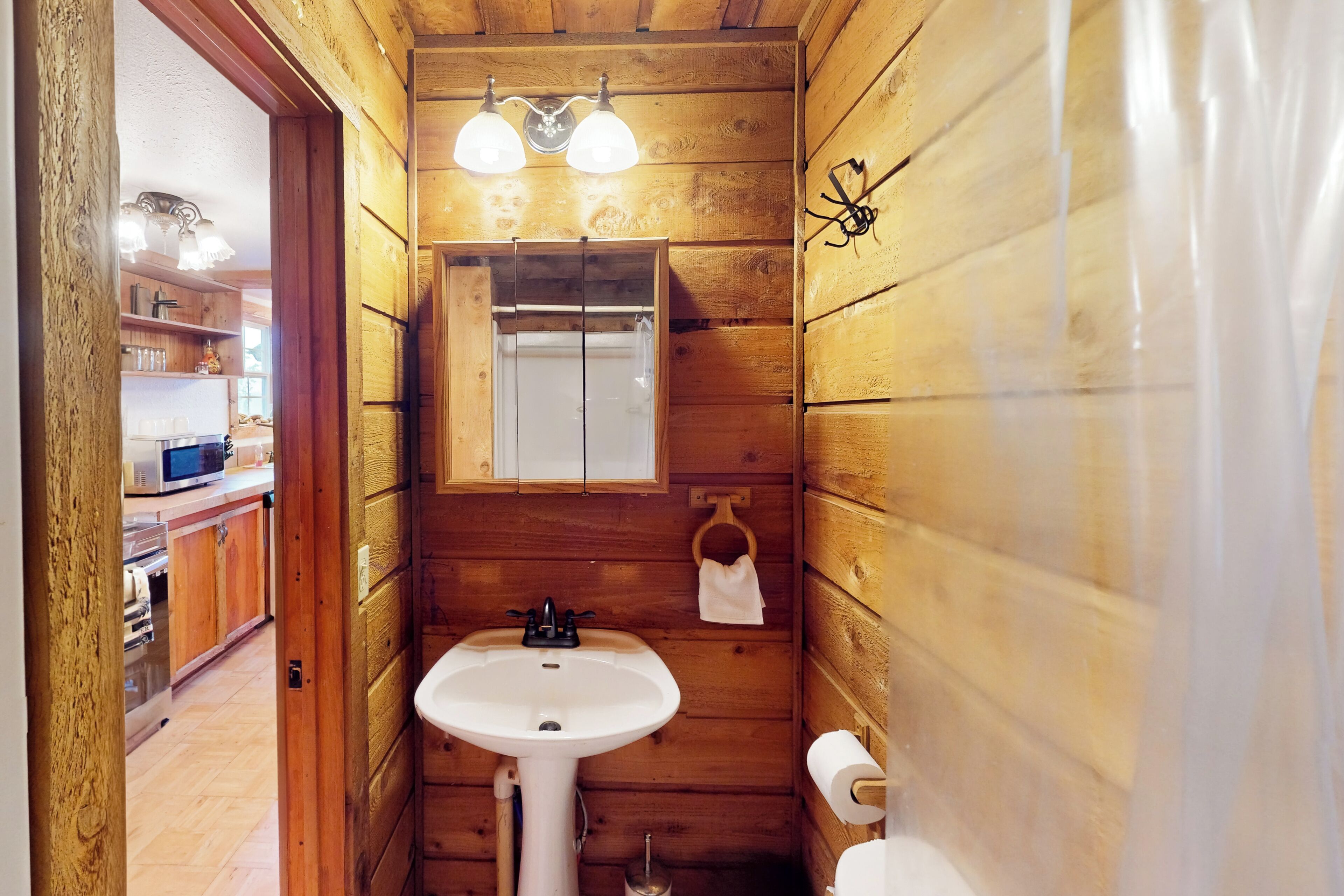 A wooden cabin bathroom with a sink, toilet, and a mirror above the sink.