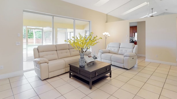 Een ruime woonkamer met een beige bank, een witte fauteuil en een donkerhouten salontafel.