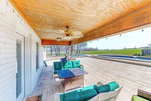 A covered patio with a ceiling fan, outdoor furniture, and a view of a swimming pool. - Dog-Friendly Cameron Home w/ Pond + Poolside Patio (Cameron)