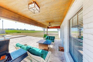 A covered patio with outdoor furniture, a grill, and a view of the surrounding landscape. - Dog-Friendly Cameron Home w/ Pond + Poolside Patio (Cameron)