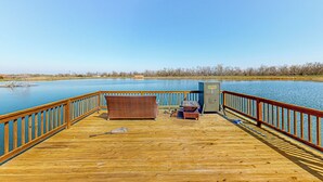 Um deck de madeira com corrimão, um sofá de vime e uma pequena mesa.