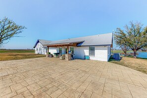 A house with a covered patio, a small porch, and a view of a lake. - Dog-Friendly Cameron Home w/ Pond + Poolside Patio (Cameron)