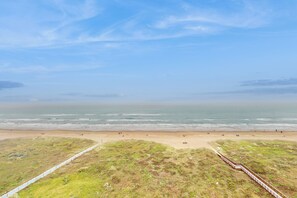 A beach with a wooden boardwalk leading to the shore, grassy dunes, and a clear blue sky. - 2BR PH, Epic Gulf Views: Suntide III - Unit 1104 (South Padre Island)