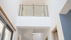 Un interior moderno con una escalera que sube a un balcón en el segundo piso.
