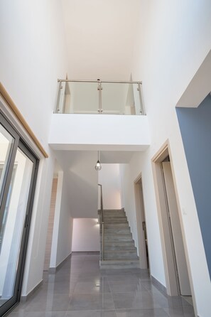 Ein modernes Interieur mit einer Treppe, die zu einem Balkon im zweiten Stock führt.
