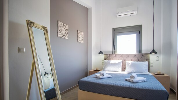 Un dormitorio con una cama, un espejo grande, dos lámparas de pared y una ventana.