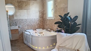Une salle de bain moderne avec une baignoire sur pieds, un meuble-lavabo et une grande plante en pot.