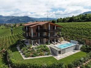 Una casa de dos plantas con balcón, piscina y un viñedo al fondo.