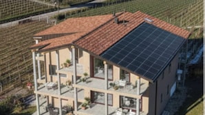 A modern multi-story house with a solar panel roof, surrounded by vineyards and mountains. - New vacation apartments in the middle of the vineyards (Eppan an der Weinstraße)