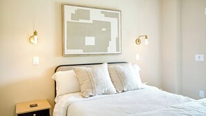 A neatly arranged bedroom with a bed, bedside tables, and a wall-mounted abstract artwork. - NEW - Luxury Mountain Retreat - Walk to Redtail Vineyard (Blairsville)