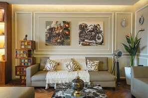 A living room with a sofa, a coffee table, and two wall-mounted paintings. - MG Luxury Stays (Panchkula)
