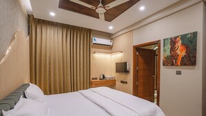 A neatly made bed with white linens, a wooden headboard, and a ceiling fan. - MG Luxury Stays (Panchkula)