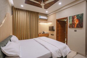 A neatly made bed with white linens, a wooden headboard, and a ceiling fan. - MG Luxury Stays (Panchkula)