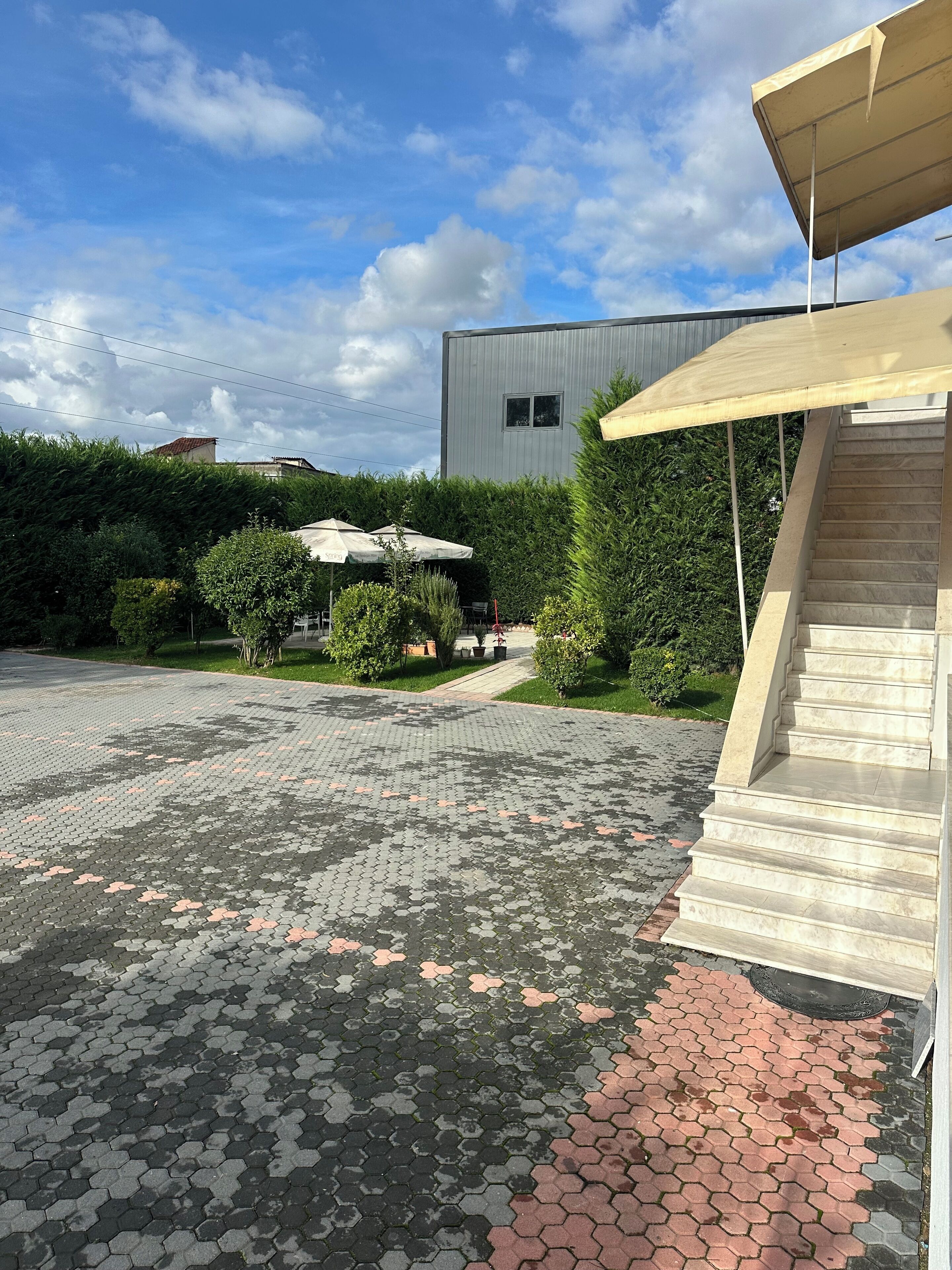 A paved courtyard with hexagonal tiles, a staircase, and a building with a metal exterior.