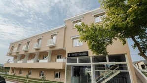 Ένα σύγχρονο ξενοδοχείο με επίπεδη πρόσοψη, πολλά μπαλκόνια και μια επιγραφή που γράφει «SWEET HOTEL».