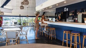Een bar met een toonbank, krukken en uitzicht op de omgeving.