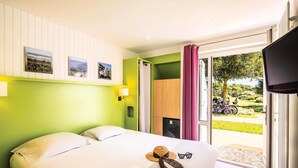 Hotelkamer met een bed, een raam met uitzicht op het omliggende landschap, een televisie en een deur naar een balkon.