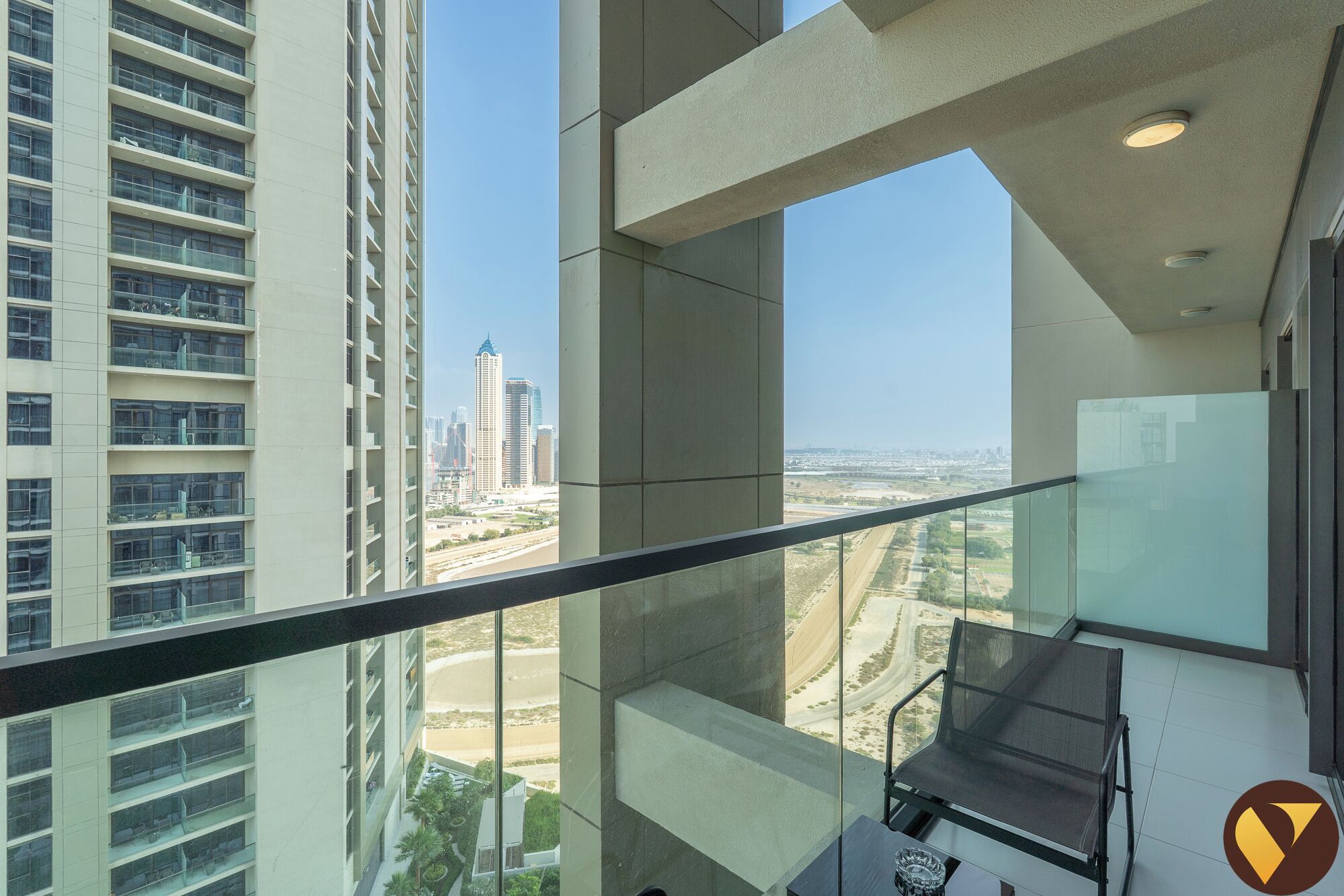 A high-rise building with a balcony, offering a view of a cityscape and a beach.