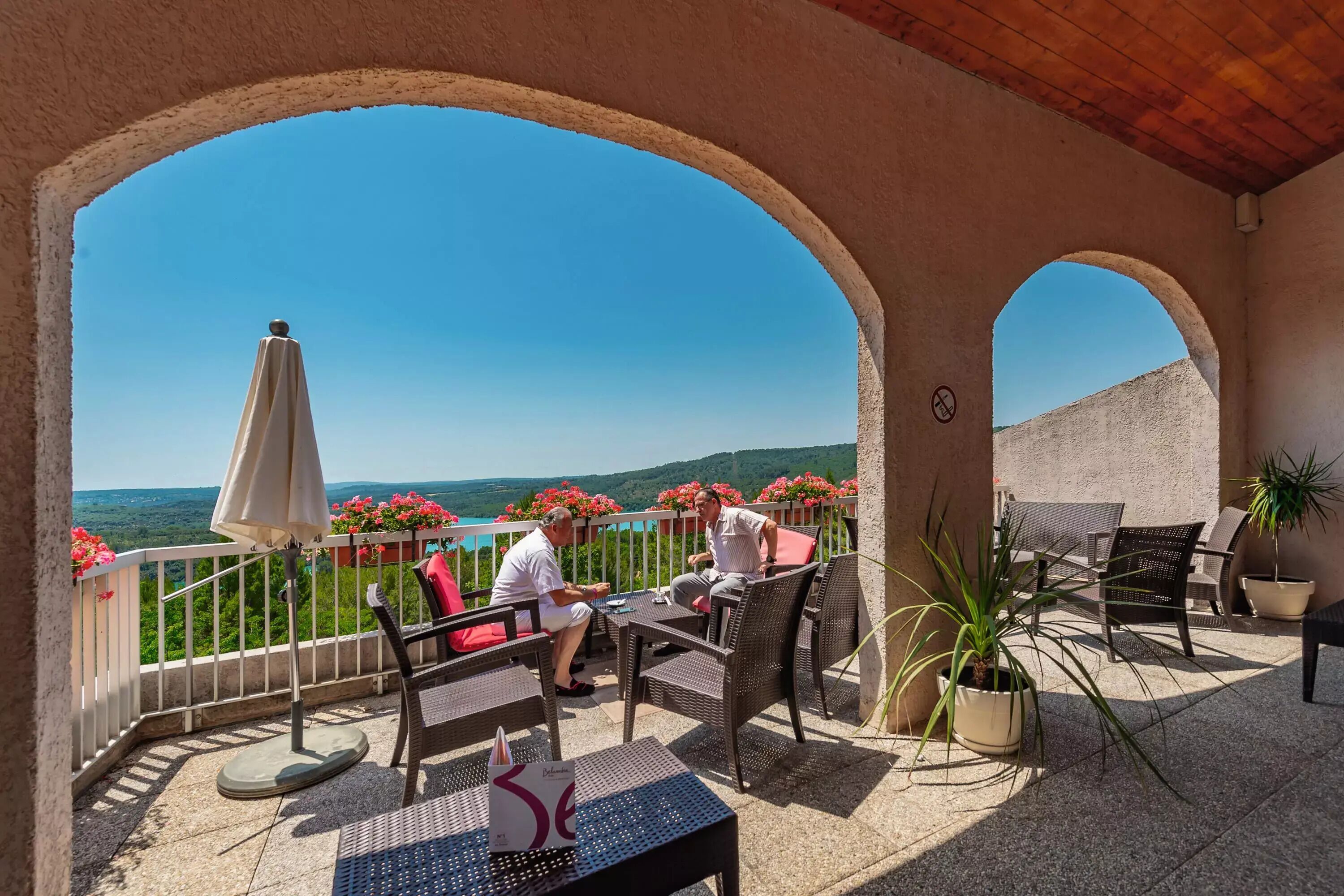 A covered outdoor seating area with a view of a mountainous landscape.