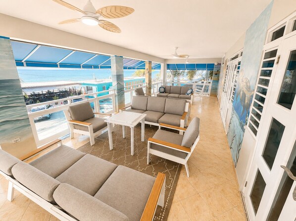 A spacious balcony with a view of the sea, furnished with sofas and a table.