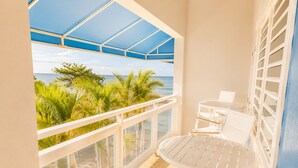A balcony with a view of the ocean, white chairs, and a table. - Extra Large Two Story Oceanfront Home | 10 mins from Rincón & Aguadilla | ON THE BEACH SLEEPS 24 PLUS (Bo Espinar Aguada)