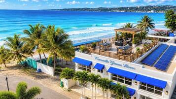 Un hotel frente a la playa con piscina, zona de estar exterior y paneles solares.