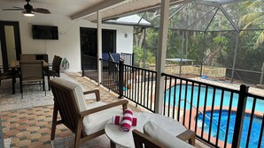 A balcony with a pool, chairs, and a table. - 3 bed/2 bath pool home & hot tub in Naples. Great neighborhood. 3 miles to beach (Naples)