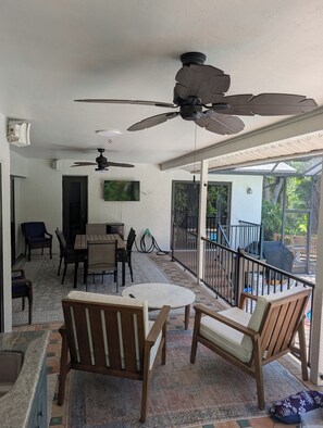 A sunlit patio area with a dining table, chairs, and ceiling fans. - 3 bed/2 bath pool home & hot tub in Naples. Great neighborhood. 3 miles to beach (Naples)