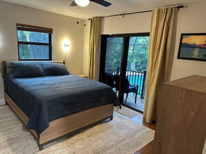 A bedroom with a bed, a nightstand, a desk, a window, and a view of a balcony with a pool. - 3 bed/2 bath pool home & hot tub in Naples. Great neighborhood. 3 miles to beach (Naples)