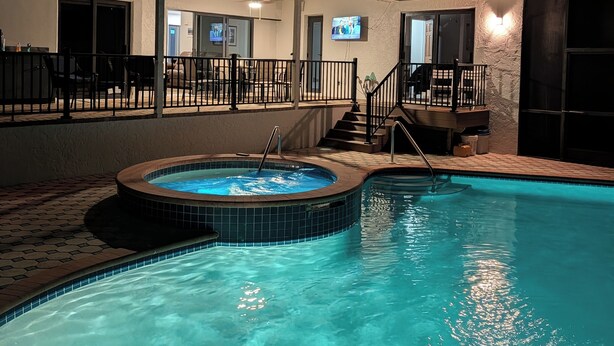 A swimming pool with a hot tub, a covered patio area, and a television screen. - 3 bed/2 bath pool home & hot tub in Naples. Great neighborhood. 3 miles to beach (Naples)