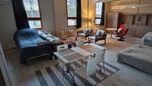 Een moderne hotelkamer met een bed, een bank, een eettafel en een rode stoel.
