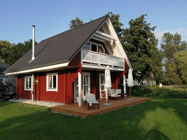 A two-story house with a balcony, a chimney, and a small porch area with outdoor furniture. - Cozy "Heimathafen" vacation home in Wiek on Rügen, right on the waterfront (Wiek)