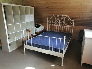 A room with a metal bed frame, a white wardrobe with open doors, and a wooden wall. - Cozy "Heimathafen" vacation home in Wiek on Rügen, right on the waterfront (Wiek)