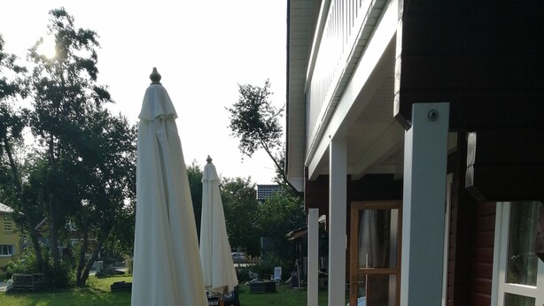 A wooden deck with outdoor furniture, including a sofa and a table, and two umbrellas.