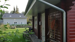 A house with a red exterior, a visible gutter, a garden with stepping stones, and a parked bicycle.