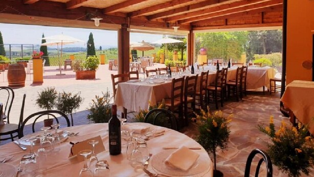 An outdoor dining area with tables set for a meal, surrounded by potted plants and a view of the countryside. - Agriturismo Tenuta Isola Verde (Cerreto Guidi)
