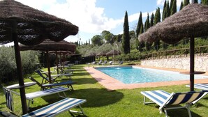 A pool area with lounge chairs and thatched umbrellas. - Agriturismo Tenuta Isola Verde (Cerreto Guidi)