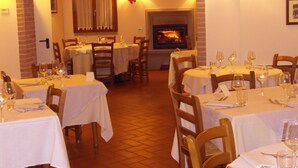 A cozy restaurant with multiple tables, wooden chairs, and a fireplace in the background. - Agriturismo Tenuta Isola Verde (Cerreto Guidi)
