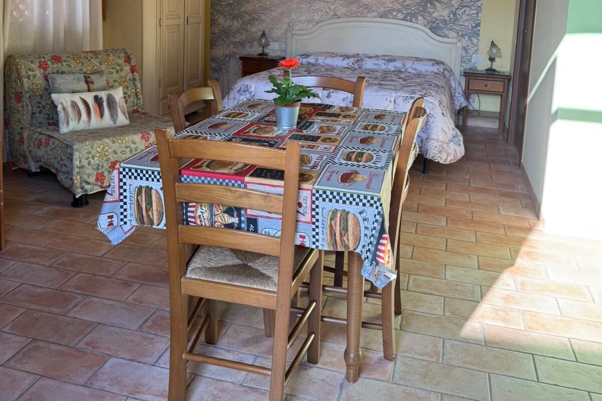 Een kamer met een bed, een eettafel met stoelen, een houten plafond en een muur met een muurschildering.