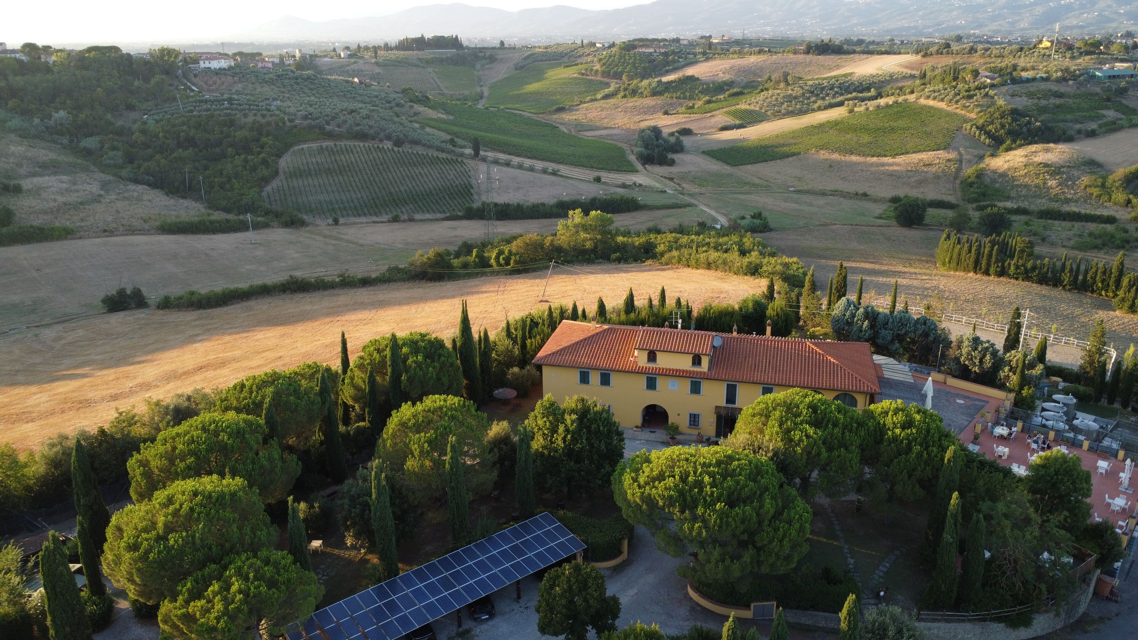 A rural property with a yellow building, solar panels, and surrounding fields.
