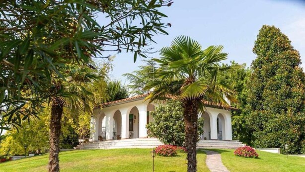 Un edificio blanco con un patio central, rodeado de palmeras y céspedes cuidados.