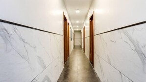 Un couloir aux murs de marbre et aux portes en bois, qui mène à une pièce.