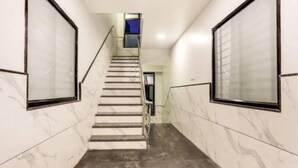 Un escalier moderne aux murs de marbre et au plancher foncé, menant à une pièce dont un des murs est peint en bleu.