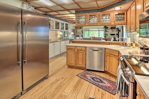 A modern kitchen with wooden cabinets, stainless steel appliances, and a large island.